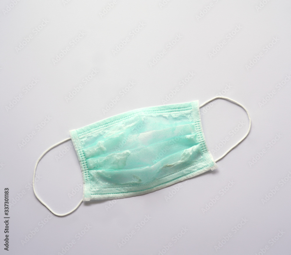 A green surgical face mask has been washed and reused. The surface's showing broken fibers. It can not protect virus or germs. During Corona pandemic, shortage problem occurs. A green surgical face mask has been washed and reused. The surface's showing broken fibers. It can not protect virus or germs. During Corona pandemic, shortage problem occurs.