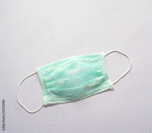 A green surgical face mask has been washed and reused. The surface's showing broken fibers. It can not protect virus or germs. During Corona pandemic, shortage problem occurs. 