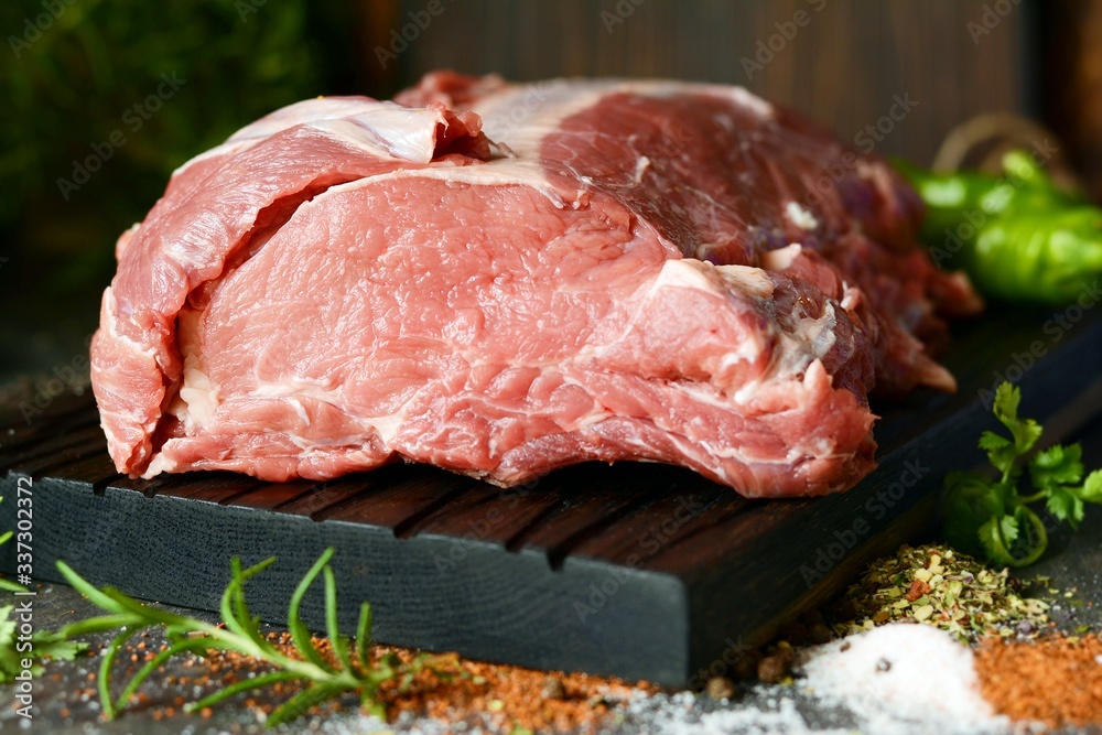 Fresh raw pork loin on the bone on a wooden board with herbs, spices and sea salt. meat for grilling. BBQ.A good piece of meat for cooking dinner. Fresh raw pork loin on the bone on a wooden board with herbs, spices and sea salt. meat for grilling. BBQ.A good piece of meat for cooking dinner.