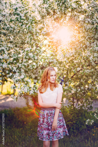 Model with red hair posing in a blooming apple tree.