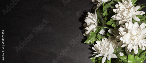 Funeral symbol. A bouquet of white flowers on the side, black background, free space for text. photo