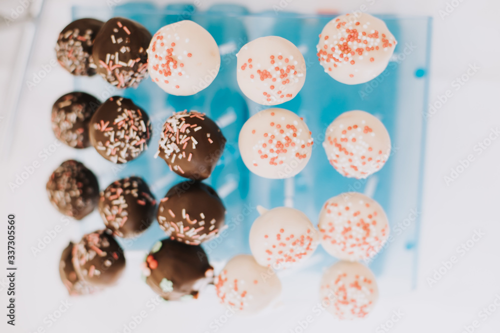 Colorful cake pops with sprinkles over a teal blue background