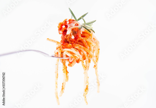 Spaghetti bolognese sprinkled with cheese and decorated with a rosemary twig on a fork on a white background