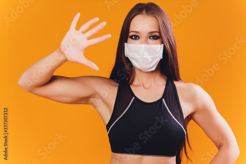 Coronavirus. COVID-19. Young beautiful woman doing sport at home during quarintine with mask protection. Stay at home activities. prevent infection from the pandemia. Healthy at home. photo
