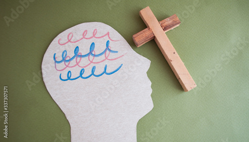 Encephalography brain cutout paper and wooden cross on a green background, awareness of epilepsy, convulsive disorder, mental health concept, World Parkinson's Day, World Alzheimer's Day. Prayer Day photo