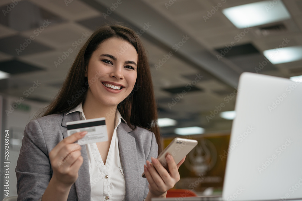 Businesswoman holding credit card, using smartphone for online shopping, sitting in office. Freelancer receive payment, check balance. Smiling woman ordering food, booking tickets on website Businesswoman holding credit card, using smartphone for online shopping, sitting in office. Freelancer receive payment, check balance. Smiling woman ordering food, booking tickets on website
