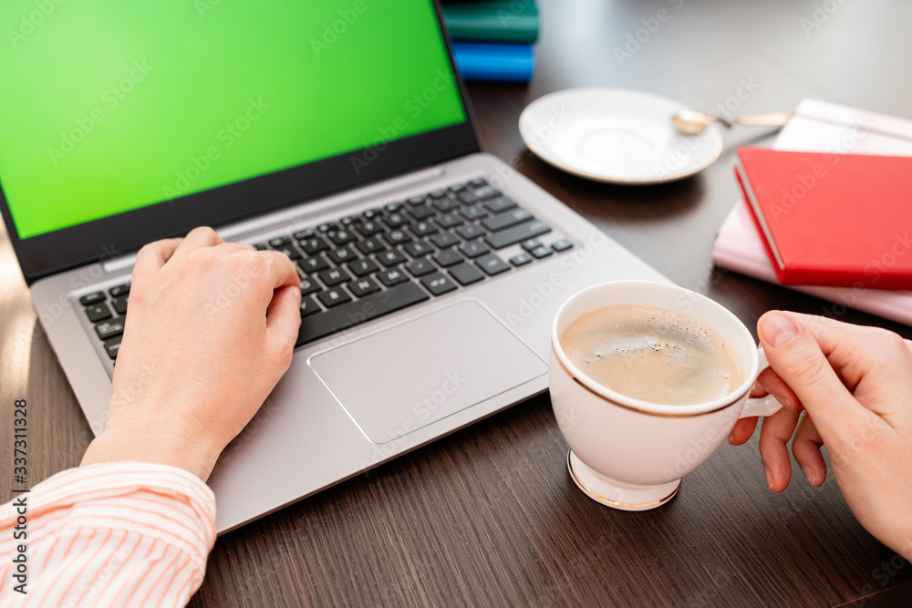 Woman hands typing laptop computer with blank screen for mock up template background, business technology and lifestyle background concept. She is drinking coffee. Woman hands typing laptop computer with blank screen for mock up template background, business technology and lifestyle background concept. She is drinking coffee.