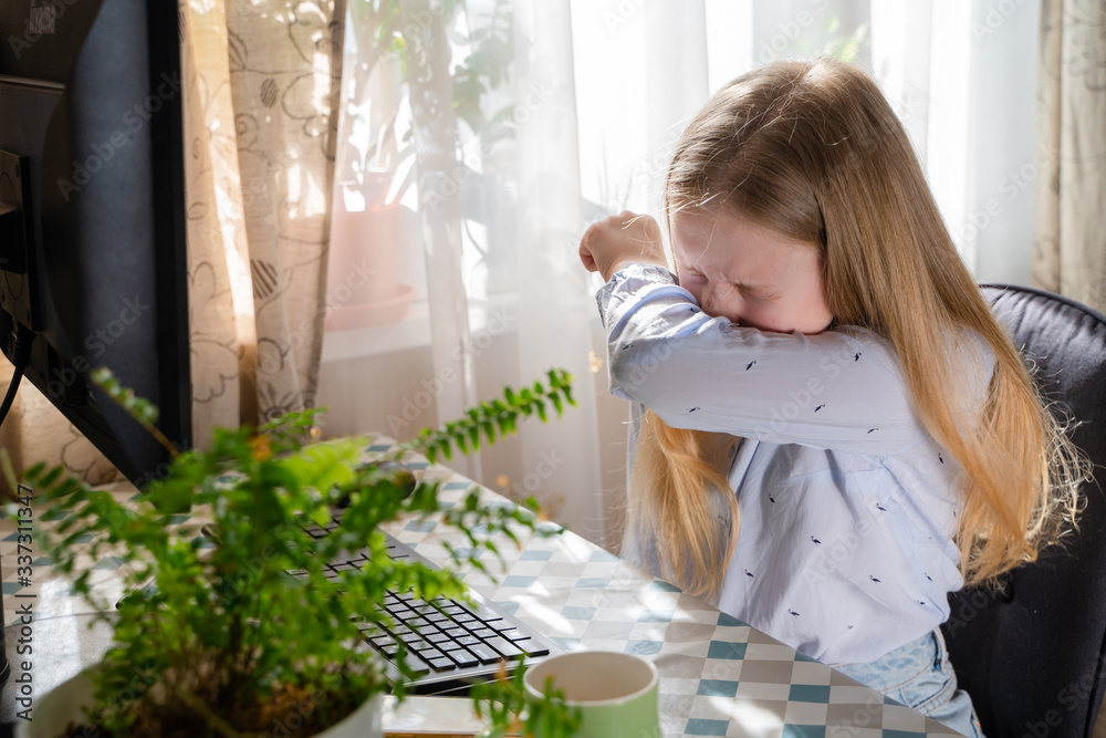 Caucasian young girl sneezing,coughing into her sleeve or elbow to prevent spread Covid-19, virus,sick girl has flu,fever covering nose,mouth with her arm from dusty,allergies,air pollution Caucasian young girl sneezing,coughing into her sleeve or elbow to prevent spread Covid-19, virus,sick girl has flu,fever covering nose,mouth with her arm from dusty,allergies,air pollution