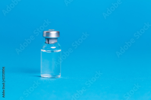 Closeup vaccine bottle on blue isolated background. Lack of coronovirus vaccine.