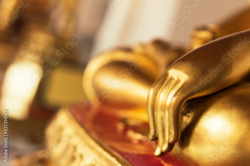 Background buddha face head body hands in buddhist temple with isolated wall. Thai old woman pray for good luck, zen peaceful and holy meditation relax. Gold statue in Thailand temple to worship