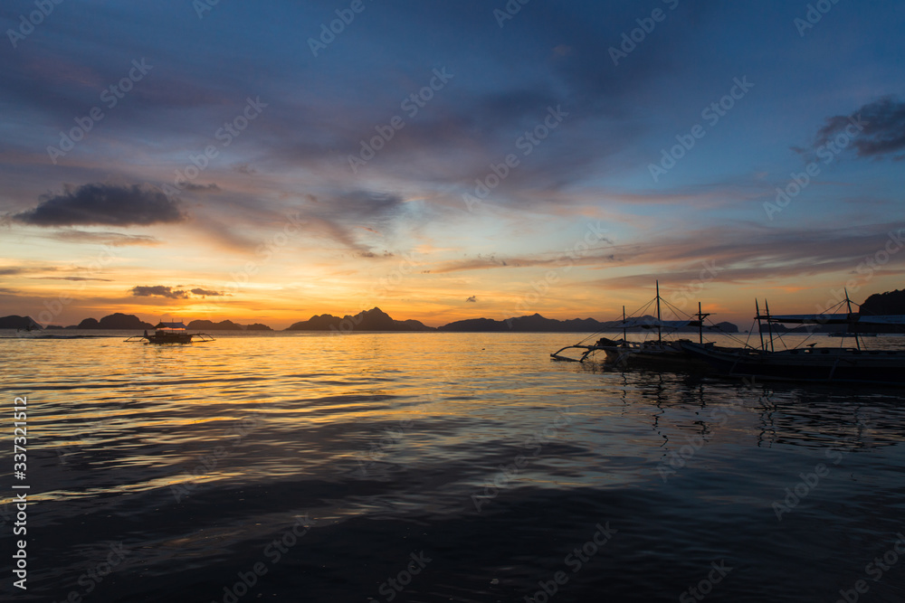 traditional philipinian boat silhouette in El Nido, Palawan with colored sunset on background