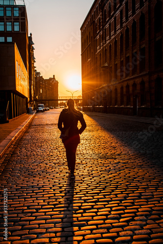 Fotografija Silhouette backview of a girl walking in the empty streets at low evening sunset light