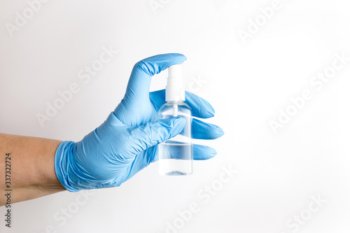 a hand in a blue disposable medical glove holds an antiseptic in the form of a spray, an alcohol solution for disinfecting surfaces, hygiene and the prevention of viral diseases