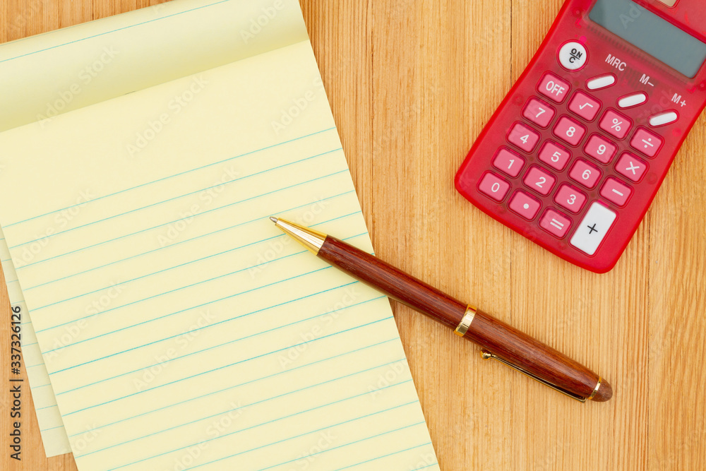 Yellow legal notepad paper with pen and calculator wood desk Yellow legal notepad paper with pen and calculator wood desk