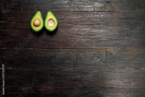 Top view of a ripe avocado halves lying on a wooden background with large area for copy space. One slice with core. Fresh food for a healthy diet.