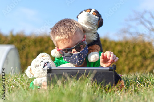 Covid 19. Boy with mask.
A young child playing outside on a tablet during a global flu pandemic.
