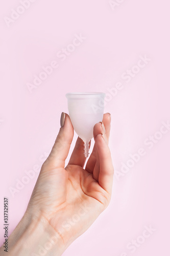 Female hand holds silicone menstrual cup. Reusable Intimate Hygiene.