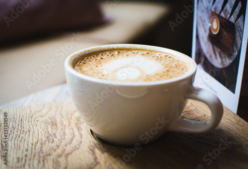 Taza de café grande con dibujo sobre la leche y fondo desenfocado