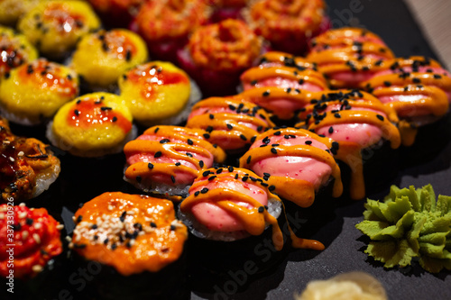 Hot baked set of rolls on a black plate with wasabi and ginger