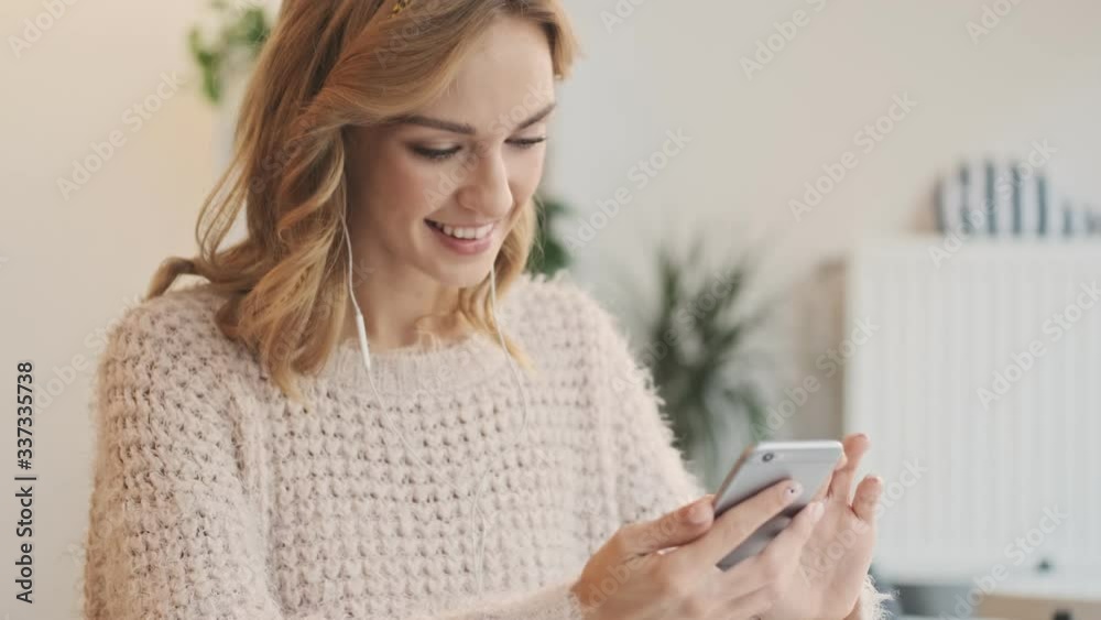 Happy smiling young blonde woman using mobile phone while drinking coffee in the white cozy cafe Happy smiling young blonde woman using mobile phone while drinking coffee in the white cozy cafe