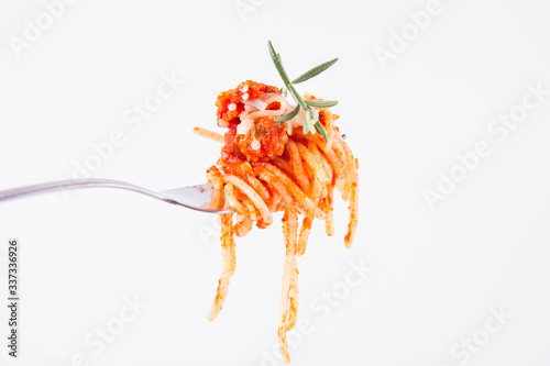 Spaghetti bolognese sprinkled with cheese and decorated with a rosemary twig on a fork on a white background 