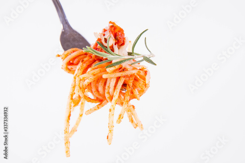 Spaghetti bolognese sprinkled with cheese and decorated with a rosemary twig on a fork on a white background 