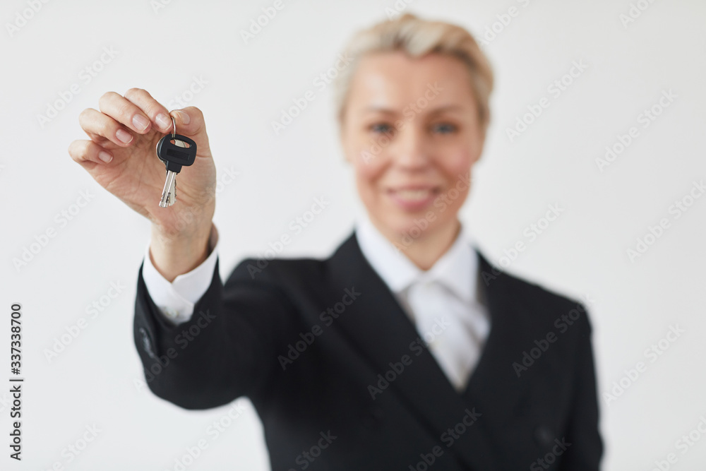 Portrait of businesswoman holding keys from new home she standing over white background
