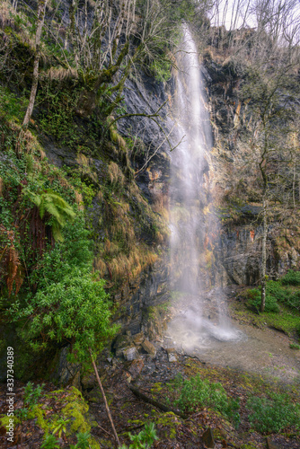 Waterfall trickles down a vegetated limestone rock wall