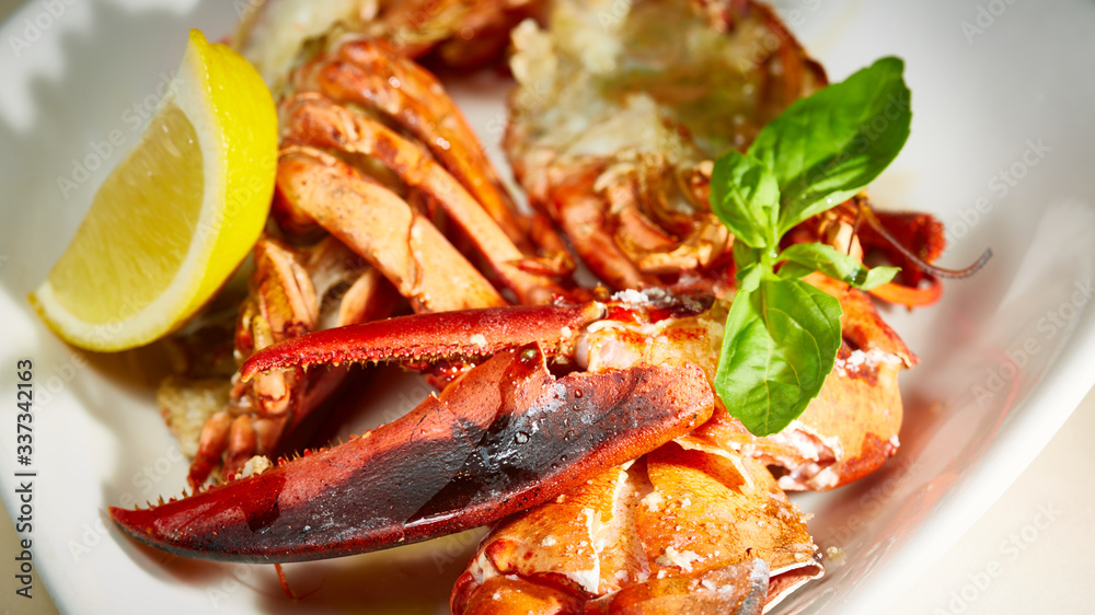 a luxury dish of lobster roasted and decorated with lemon and basil. Shallow dof a luxury dish of lobster roasted and decorated with lemon and basil. Shallow dof