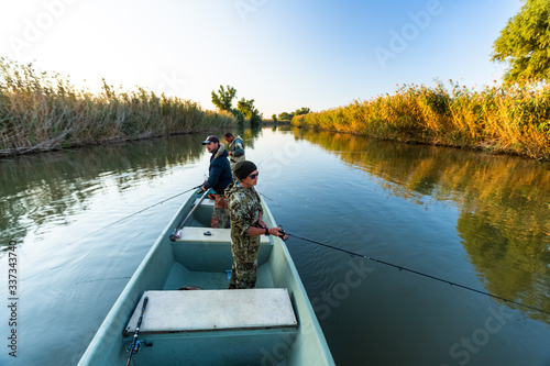 Anglers fishing from the boat on the calm river in Astrakhan Region in Russia. Astrakhan is a famous fishing destination