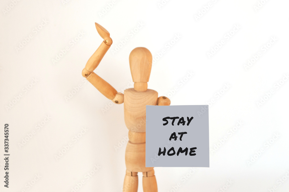 World coronavirus pandemic,2019-ncov. wooden man is isolated on a white background holds a sign with the inscription: stay home. Outbreak Defense Concept. Copy Space. World coronavirus pandemic,2019-ncov. wooden man is isolated on a white background holds a sign with the inscription: stay home. Outbreak Defense Concept. Copy Space.