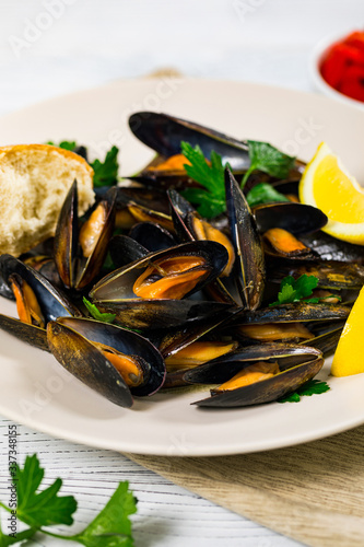 Delicious Seafood Mussels with Lemon and Parsley. Clams in the Shells on Wooden Background. Selective focus.
