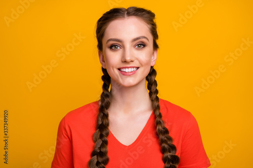 Closeup photo of pretty attractive cheerful lady two cute long braids good mood beaming smile wear casual red t-shirt isolated vibrant yellow color background