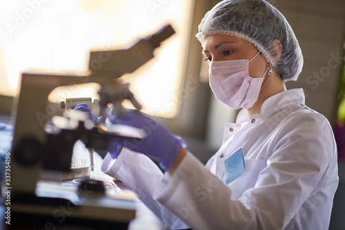 Laboratory worker looking samle through microscope photo