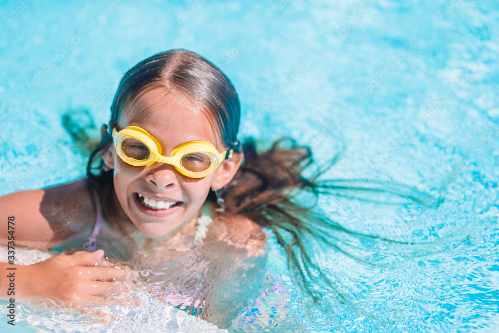 Naklejka premium Little adorable girl in outdoor swimming pool