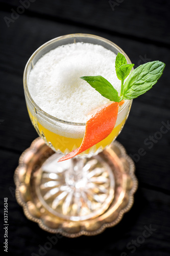 vintage style sour cocktail with egg white foam on black background