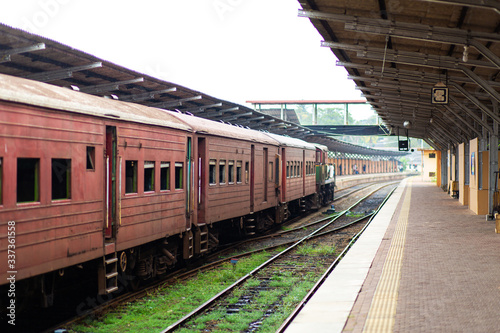 Empty platform of a railway station in Sri Lanka. Old rusty train cars. It looks like an abandoned place, but it not
