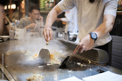 He stir fry food in a flat pan. cook tools and flat pad teppanyaki japanese food