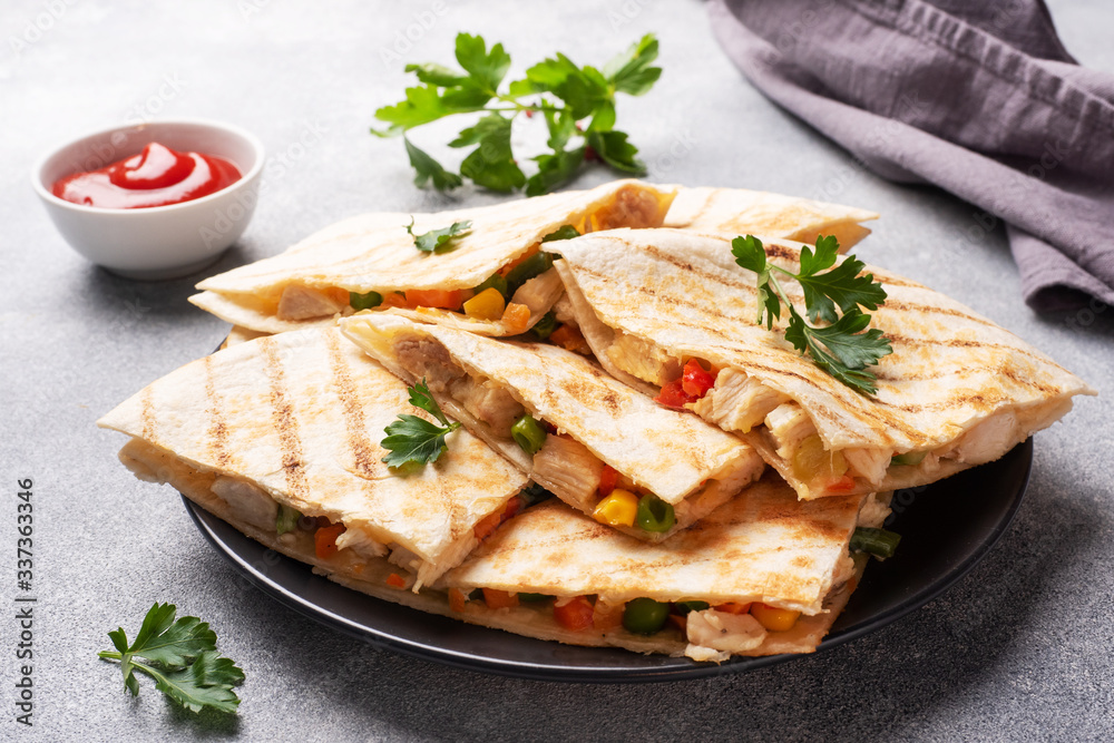 Triangular slices of a Mexican quesadilla with the sauce. The traditional dish of Mexico is tortillas stuffed with meat and vegetables. copy space. Triangular slices of a Mexican quesadilla with the sauce. The traditional dish of Mexico is tortillas stuffed with meat and vegetables. copy space.