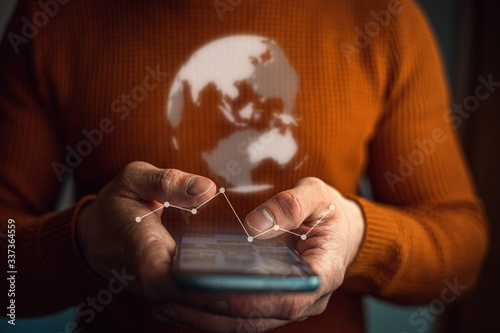 Mann hält Smartphone in den Händen, darüber schwebt ein Erdball