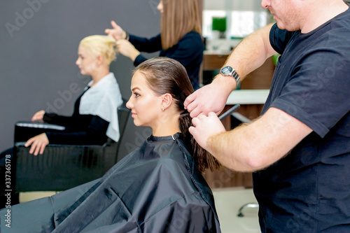 Woman receiving haircut closeup by hairdresser in hair salon.