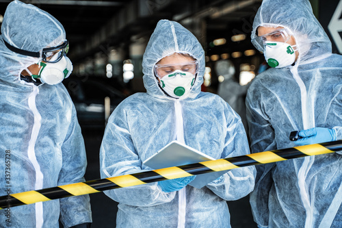 Team of healthcare workers wearing hazmat suits working together to control an outbreak in the city photo