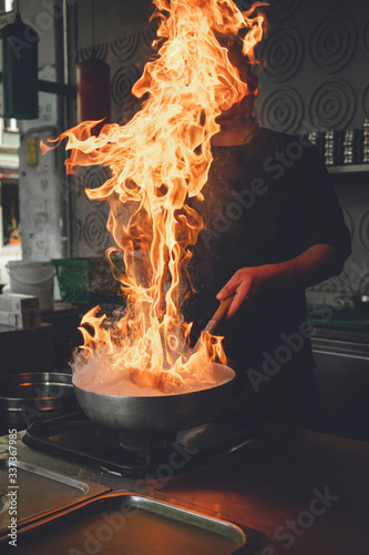 chef in action with a frying pan on high heat