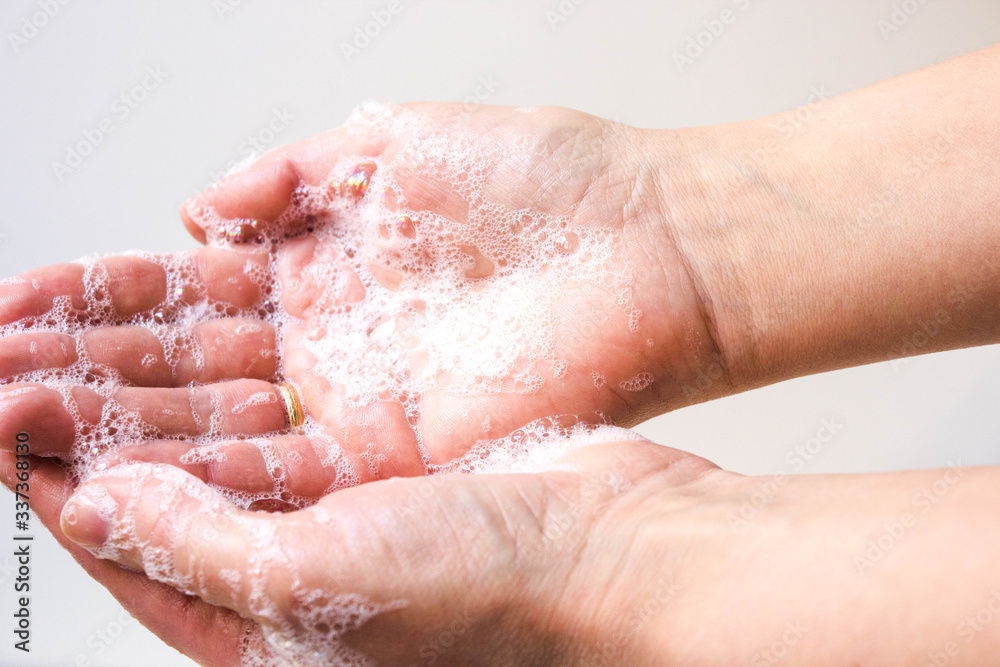 Hygiene and protection of hands from viruses (coronavirus) and bacteria using soap. Women's hands with foamed soap close-up on a white background. The process of properly washing hands with soap. Hygiene and protection of hands from viruses (coronavirus) and bacteria using soap. Women's hands with foamed soap close-up on a white background. The process of properly washing hands with soap.