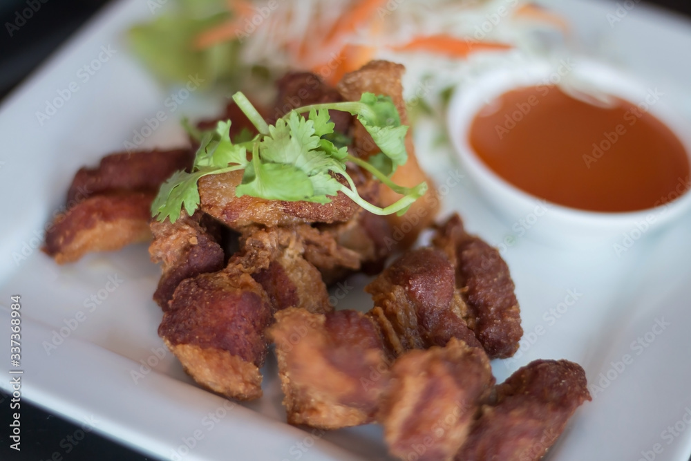Deep fried pork belly served with sauce and salad