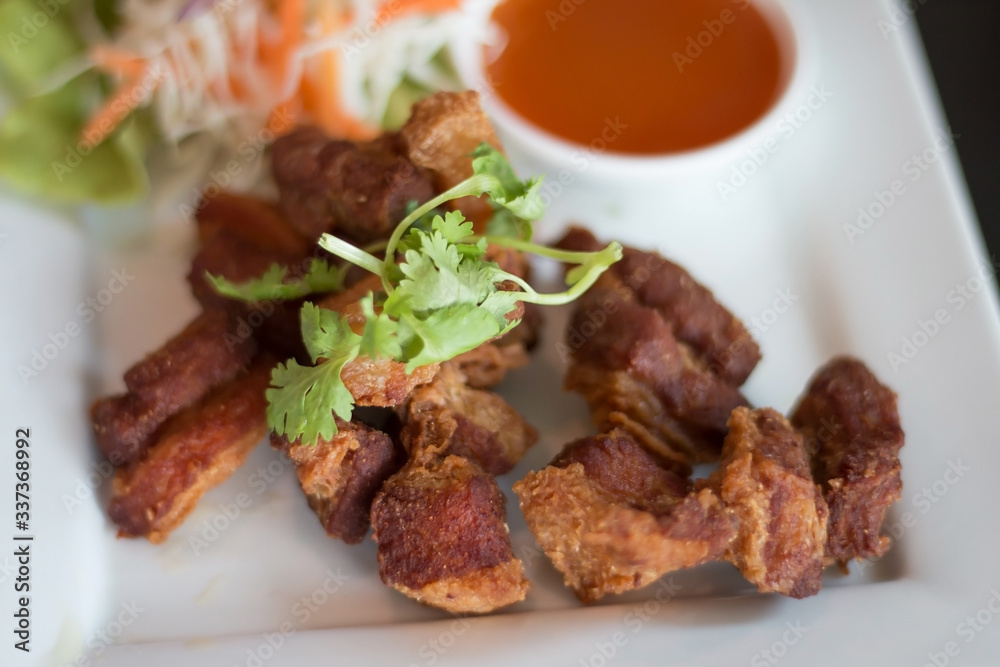 Deep fried pork belly served with sauce and salad