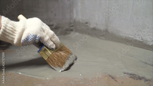 Foto Workers cover the concrete screed with mortar and make waterproofing