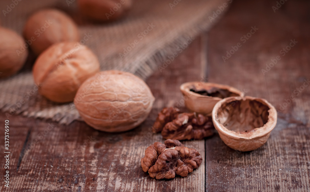 walnuts are scattered. They lie on a canvas material on an old wooden background walnuts are scattered. They lie on a canvas material on an old wooden background
