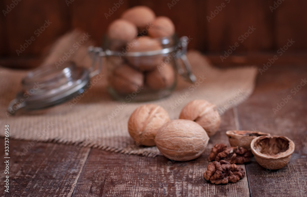 walnuts fall out of a glass jar. They lie on a canvas material on a worn wooden background walnuts fall out of a glass jar. They lie on a canvas material on a worn wooden background