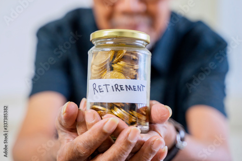 Elderly man hand showing a jar full of coins